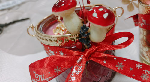 świeczka sojowa, ozdobiona motywami świątecznymi, grzybkami i wstążką